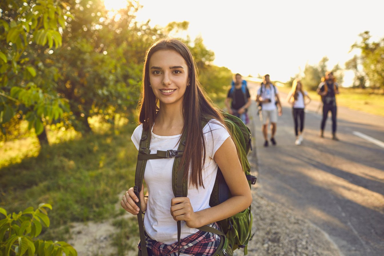 Hiker Girl with a Backpack Smiles on an Excursion in a Travel in Nature. Hiking Tourism